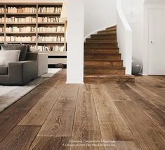 a living room filled with furniture and bookshelves next to a stair case full of books