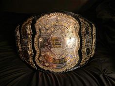 a gold and black wrestling belt sitting on top of a bed