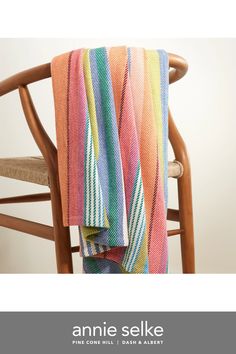 an orange, pink, blue and green striped towel sitting on top of a wooden chair