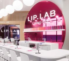 a room filled with lots of white tables and chairs next to a pink sign that says lip lab