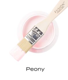 a white paint brush sitting on top of a pink bowl with the word peony written below it