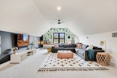 a large living room with white carpeting and black walls, along with an area rug on the floor