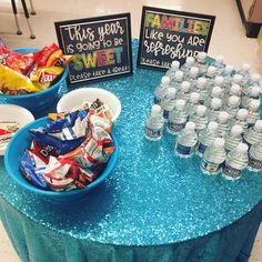 a table topped with lots of water bottles and bowls filled with candy bar wrappers