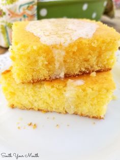 two pieces of yellow cake sitting on top of a white plate next to a cup