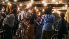 a group of people standing around each other in a room with lights on the ceiling