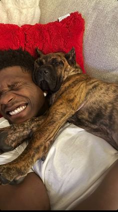 a man laying on top of a bed next to a brown and white dog with it's mouth open