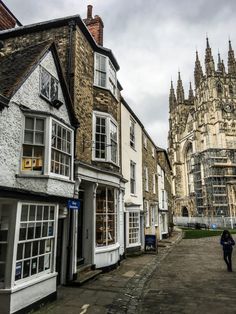 a person walking down the street in front of some old buildings on a cloudy day