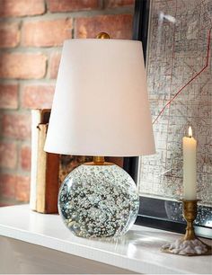 a table with a lamp on it next to a brick wall and a framed map