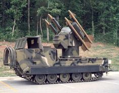 an armored vehicle carrying wooden planks on its back in front of some trees and bushes