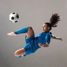 a young woman kicking a soccer ball in the air with her legs spread wide out