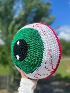 someone is holding up a crocheted ball in the shape of a eyeball