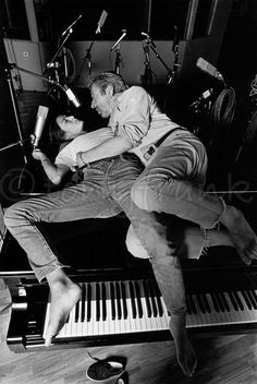 a man sitting on top of a piano next to a woman