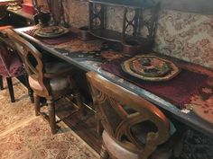 a dining room table with chairs and plates on it in front of a wallpapered wall