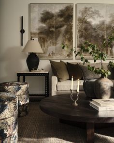 a living room filled with furniture and two paintings on the wall above it's coffee table