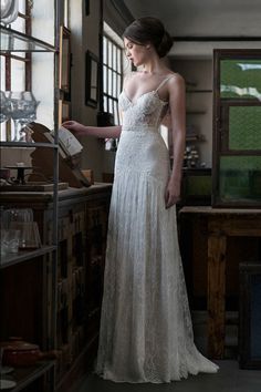 a woman in a white dress is looking at something on the shelf next to her