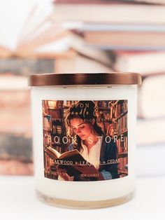 a candle with a picture of a woman reading a book on top of bookshelves