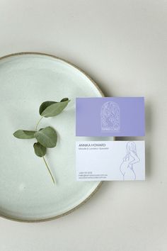 a white plate topped with a green plant next to a business card on top of it