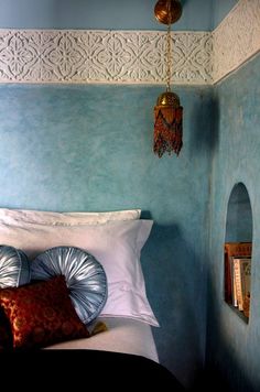 a bed in a room with blue walls and white trimmings on the headboard