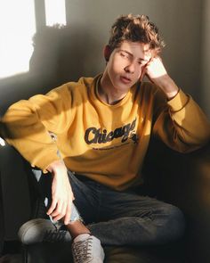 a young man sitting in a chair with his hand on his head and looking off to the side