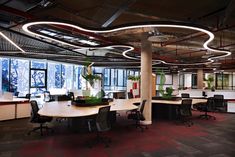 an empty office with desks, chairs and plants in the middle of the room