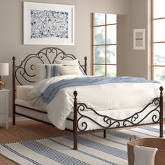 a bedroom with a metal bed frame and white linens on the carpeted floor