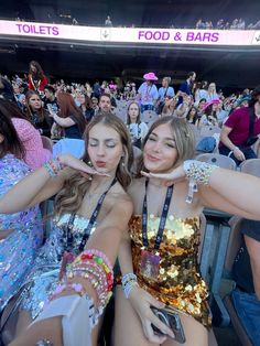 two beautiful women sitting next to each other in front of a crowd