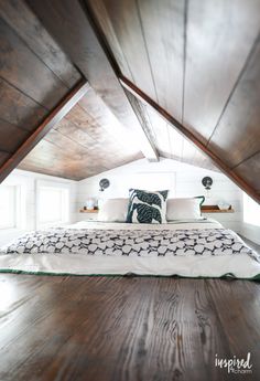 a bed sitting in the middle of a room under a roof with wooden beams on it