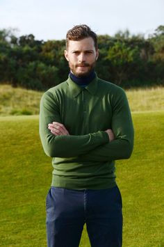 a man with his arms crossed standing in the grass