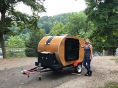 a woman standing next to a small trailer