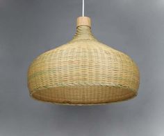 a wicker light fixture hanging from a white cord on a gray background with grey clouds in the sky