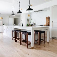 a kitchen island with three stools in front of it and lights hanging from the ceiling