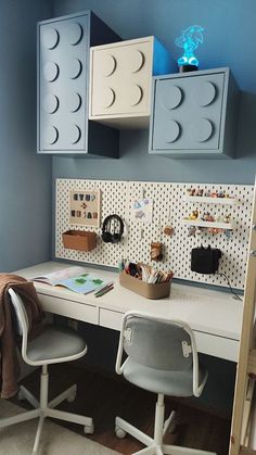 a white desk topped with a computer monitor next to a wall mounted legos on it