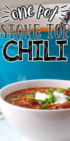 a white bowl filled with chili and sour cream on top of a blue tablecloth