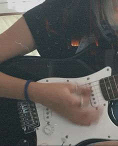 a woman playing an electric guitar in her living room