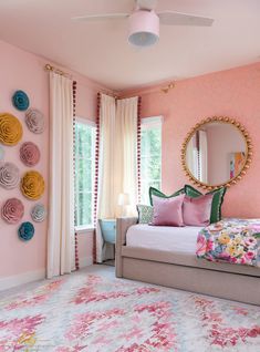 a bedroom decorated in pink, yellow and green with flowers on the wall behind the bed