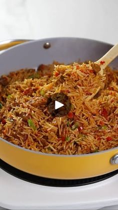 a yellow pan filled with rice and meat on top of a white stove burner