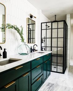 a bathroom with green cabinets and marble counter tops, along with a large mirror on the wall