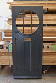 a black door sitting next to stacks of wood