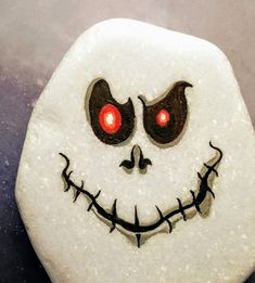 a close up of a rock with a face painted on it and eyes glowing in the dark