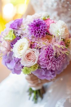 a bride holding a bouquet of purple and white flowers