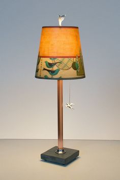 a lamp with a bird on it and a red lampshade hanging from the side