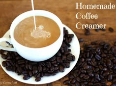 a cup of coffee sitting on top of a white saucer filled with coffee beans