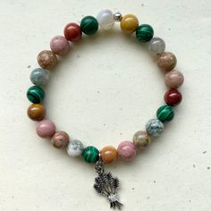 a beaded bracelet with a tree charm on the front and an elephant charm on the back