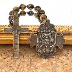 This stunning single decade features golden-brown tiger eye gemstones and solid bronze pieces cast from antiques using the lost wax method. The front of the 2" cross features St. Michael in battle. The reverse side depicts angels kneeling in adoration before the Holy Eucharist in the monstrance. This cross pairs nicely with the handsome St. Benedict Crucifix which also measures 2” in length. A perfect gift for anyone with a devotion to St. Michael, St. Benedict, or for Confirmation, or a priest. Brown Crucifix Spiritual Jewelry, Spiritual Brown Crucifix Jewelry, Brown Spiritual Crucifix Jewelry, Antique Bronze Crucifix Jewelry, Holy Eucharist, Brown Tiger, Decade Rosary, Brown Tiger Eye, St Benedict