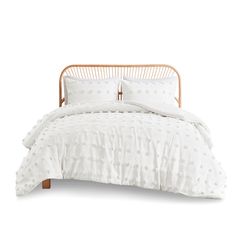 a bed with white comforter and pillows on top of it, in front of a white background