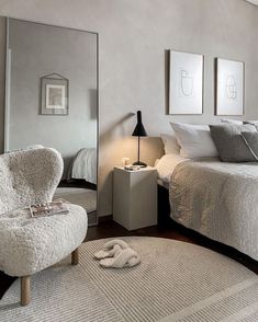 a bedroom with a bed, chair and mirror