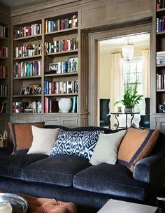 a living room filled with lots of bookshelves next to a couch and coffee table