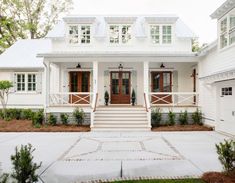 a white house with red front doors and steps leading up to the front door is shown