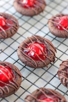 chocolate cookies covered in red jelly on a cooling rack