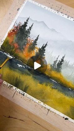 someone is painting a landscape with watercolors